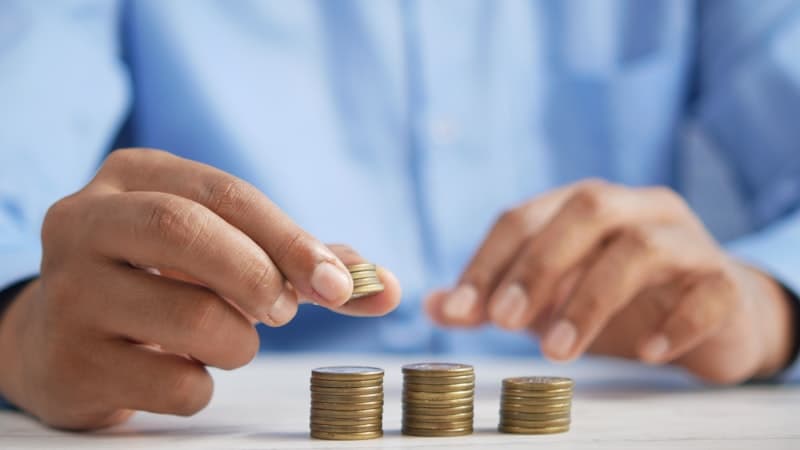 Hands stacking coins on a table to show savings growing