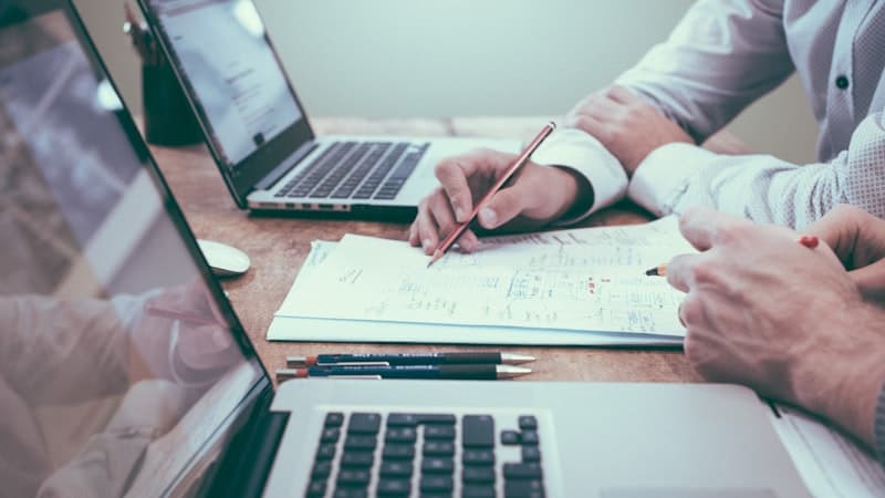 Worker checking a timesheet beside a calculator on a desk