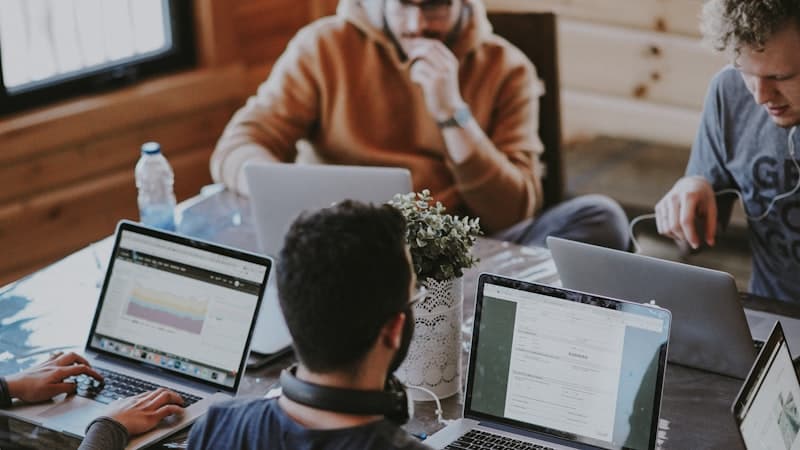 People working on laptops at a shared desk